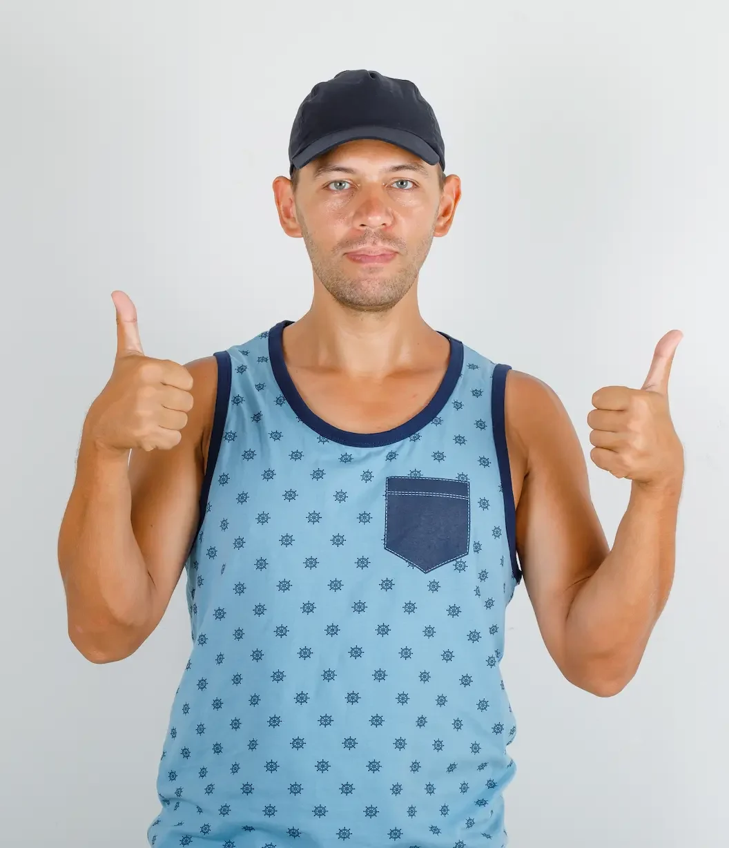 young man showing thumbs up blue singlet with cap looking happy e1725695373333